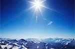 Sun over snow covered mountains