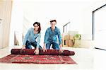 Couple unrolling carpet in new home