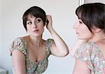 Woman examining hair in mirror