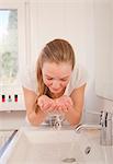 Teenage girl washing face in bathroom