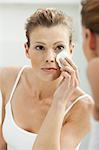 Woman cleansing her face in bathroom