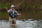 Fly fisherman casting a line in river