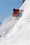 Skieur en tournant sur le visage de la montagne escarpée
