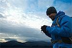 Hiker using digital camera on hillside