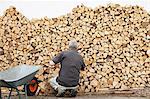 Older man piling wood into wheelbarrow