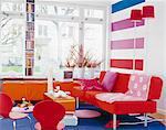 Interior of modern living room with red sofa, chairs, and bookshelf
