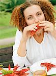 Milieu adulte femme aux cheveux roux bouclé manger des homards