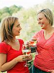 Two women holding wine glasses and talking in garden