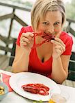 Portrait of woman sitting at outdoor table eating crayfish