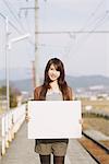 Pretty Young Woman On Platform Holding Whiteboard