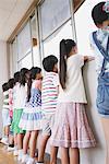 Children Looking Out Through A Window