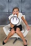 A woman yelling in a megaphone in an office, Sweden.