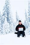 A man with a laptop in a forest a winter day, Sweden.