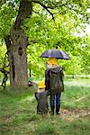 Mother and daughter walking in the rain in a park, Sweden.