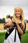 A teenage girl holding a hen, Sweden.