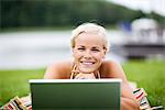 A woman lying on a lawn using a laptop, Sweden.