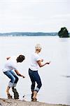 Un homme et une femme de lancer des cailloux d'essayer pour les faire rebondir sur la surface de l'eau, Suède.