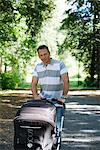 Father walking in a park with a pram a sunny day, Sweden.