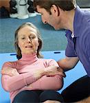 Trainer helping older woman exercise