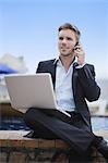 Businessman with laptop on cell phone