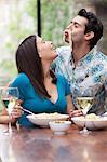 Playful couple eating together at table