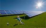 Boy playing in field by solar panels