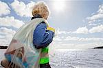 Boy hauling bag of trash on beach