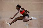 Runner jumping over hurdles on track