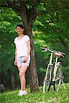 Japanese Woman Sanding By Tree Trunk With Bicycle