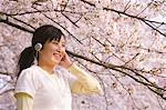 Teenage Girl Enjoying Music Under Cherry Blossom Tree