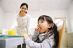 Woman Smiling While Her Daughter Eating Food