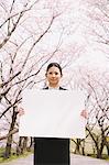 Businesswoman Holding Whiteboard With Cherry Blossoms In Background