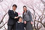 Gruppenfoto der japanischen Familie unter blühenden Kirschbäumen