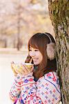 Japanese Women Leaning On Tree And Holding Cup Of Tea
