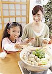 Mother and daughter sitting around Japanese hot pot