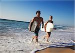 Young couple running out of ocean with bodyboards, Brighton beach, Perth, Western Australia, Australia