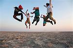 Botswana, Makgadikgadi. A family jump high in the air above the Makgadikgadi salt pans.