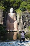Man taking photograph of replica of Leshan Big Buddha at Splendid China model village, Shenzhen, Guangdong, China