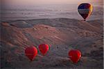 3 No. red and 1 No. multicoloured hot air balloons, ascend at dawn over the Valley of the Kings and Queens, Al Asasif, Luxor, Egypt, Africa.