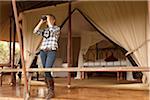 Kenya, Maasai Mara. A tourist looks out over the bush from the veranda of her luxury tented room.