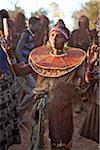 During a Ngetunogh ceremony, the mother of a Pokot initiate sings and dances holding high the cowhorn container she used to smear fat over the masks of her son and other boys as a blessing.