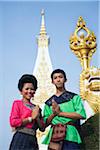 Thailand, Nakhon Phanom, That Phanom.  Dancers in ceremonial Isan dress with the chedi at Wat Phra That Phanom in the background.  The dancers perform traditional folk dances to pay religious homage during the festival of Ok Phansa (usually in October).