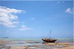 Zanzibar, Matemwe. A boat is stranded on the low tide, with Mnemba Island in the distance.