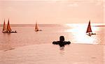 Zanzibar, Matemwe Bungalows. Un touriste se trouve au bord d'une piscine à débordement regarde les boutres.
