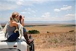 Tanzania, Ngorongoro. A tourist looks out over the Ngorongoro Crater from the bonnet of her Land Rover.
