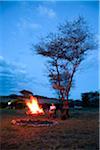 Tanzania, Serengeti. A tourist warmsup by the fire after a safari at Lemala Ewanjan.