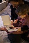 Mother holding toddler son on lap, reading bedtime story