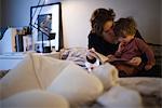 Mère tenant fils tout-petits sur genoux, lecture histoire de coucher dans son lit