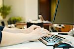 Person typing on computer keyboard, cropped