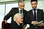 Young businessman showing mature executives how to use digital tablet